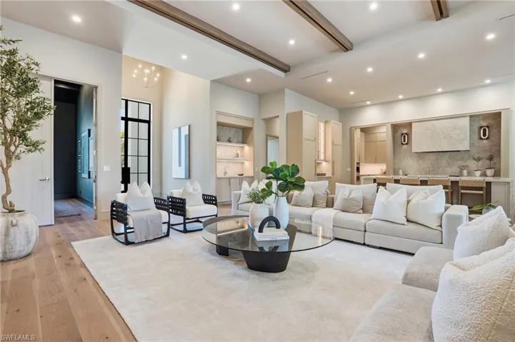 Spacious living area featuring hardwood flooring, recessed lighting, and exposed ceiling beams