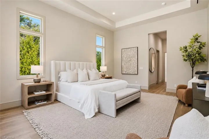 Expansive room featuring wood-finish flooring, a recessed ceiling, and multiple tall windows
