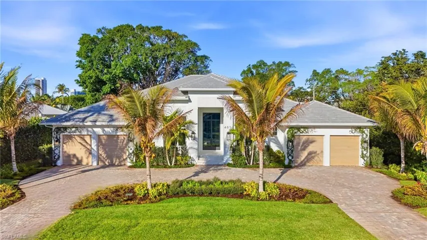Contemporary exterior featuring a paver driveway, manicured lawn, tropical landscaping, and a tile roof