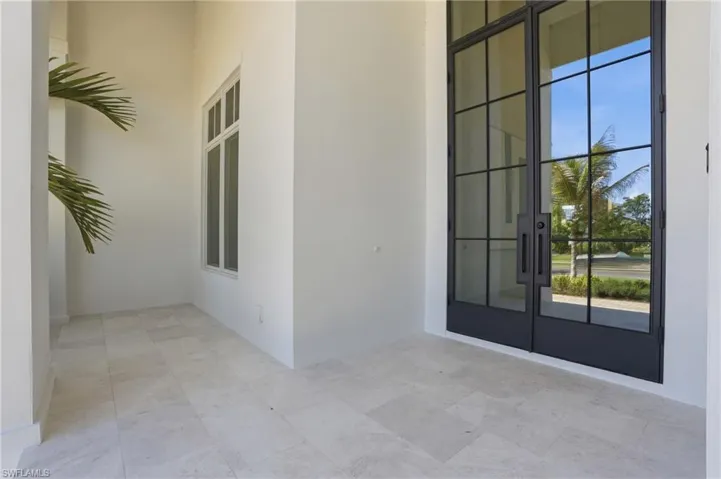 The property features a double entry door with dark frames and large glass panels, a window with a white frame, and light-colored tiled flooring