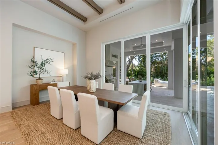 This dining area features light wood flooring, exposed ceiling beams, and a large sliding glass door