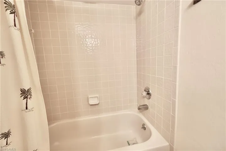 Bathroom with shower / tub combo with curtain and a textured wall