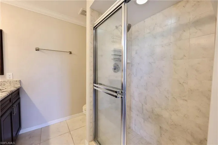 Full bathroom with vanity, crown molding, a shower stall, and light tile patterned floors