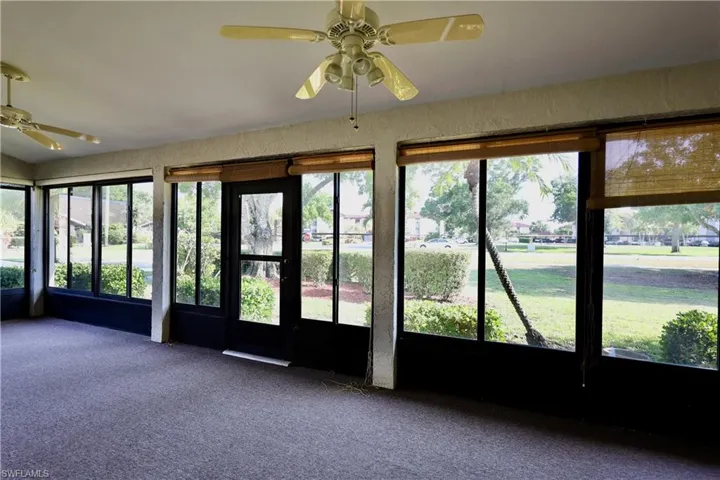 Unfurnished sunroom with ceiling fan, carpet floors, and a textured wall