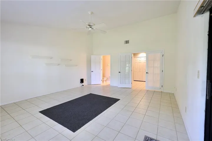 Spare room with a high ceiling, light tile patterned floors, ceiling fan, and french doors