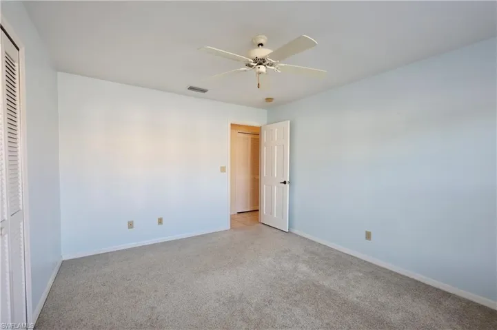 Unfurnished bedroom with light carpet, ceiling fan, and a closet