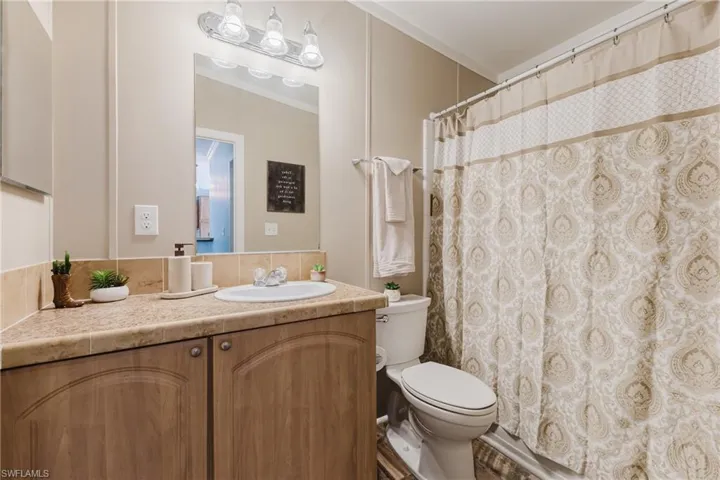 Full bath featuring toilet, vanity, ornamental molding, and a shower with curtain