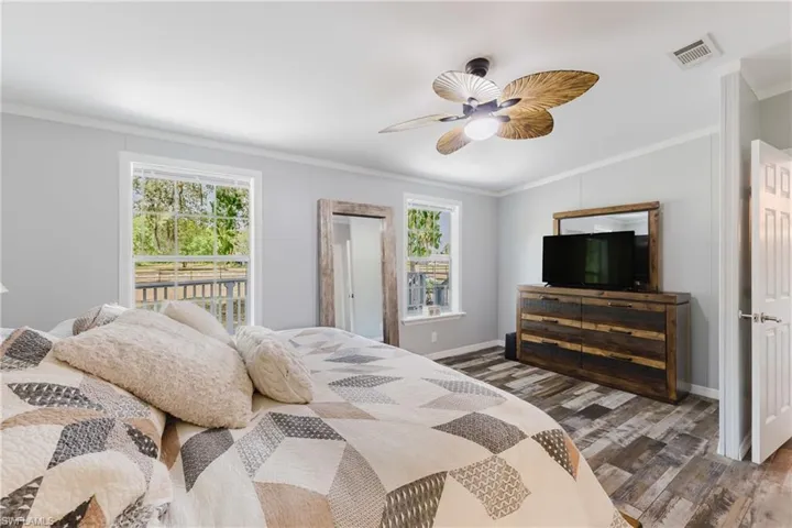 Bedroom with wood finished floors, crown molding, baseboards, and a ceiling fan
