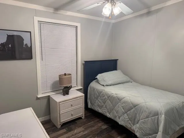 Bedroom featuring dark wood-type flooring, ornamental molding, and a ceiling fan