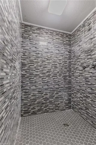 Full bathroom featuring a tile shower, a textured ceiling, and tile walls