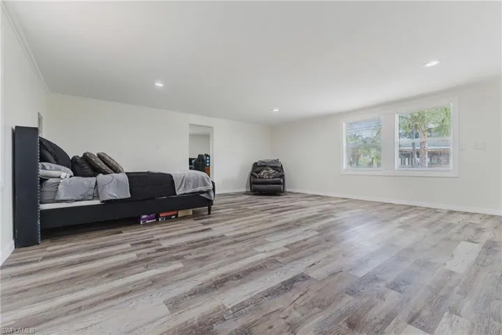 Bedroom featuring wood finished floors, recessed lighting, baseboards, and ornamental molding