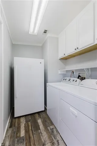 Laundry room with cabinet space, washer and dryer, and dark wood-type flooring