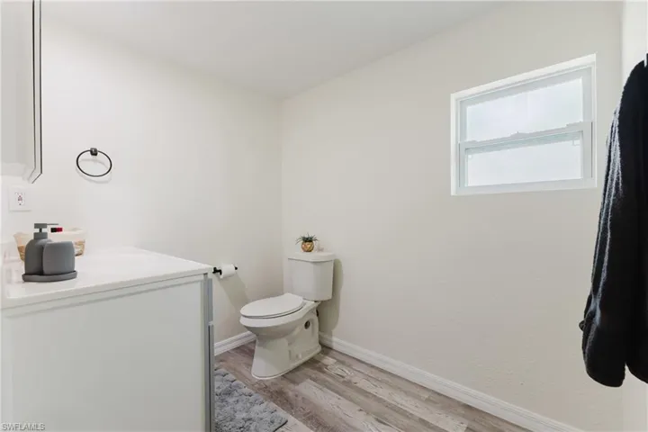 Bathroom featuring vanity, wood finished floors, toilet, and baseboards