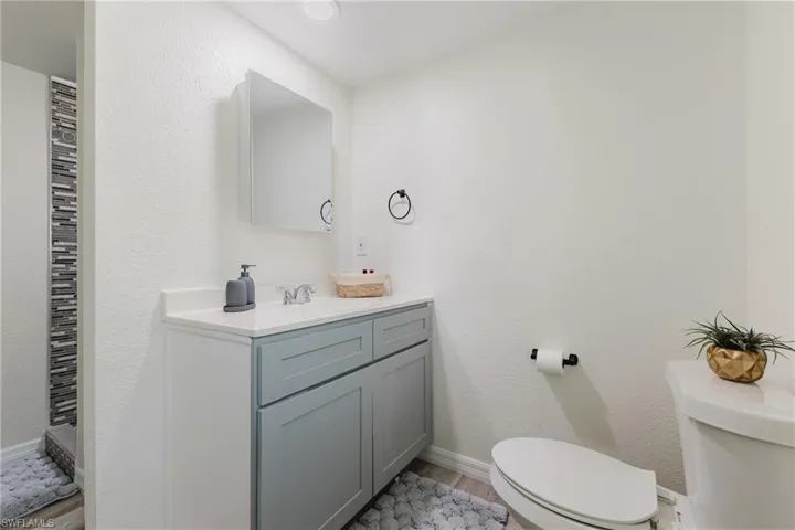 Bathroom featuring toilet, wood finished floors, vanity, and baseboards