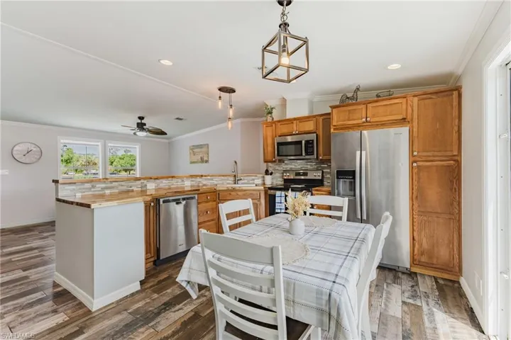 Kitchen featuring stainless steel appliances, ornamental molding, a peninsula, a sink, and decorative backsplash