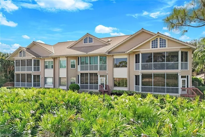 Rear exterior of the building showing screened lanai and upper-unit location (end unit).