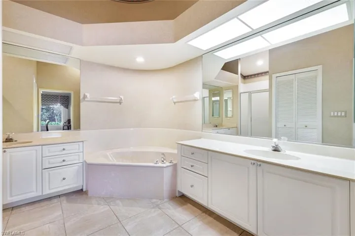 Primary bathroom with dual vanities, soaking tub, and walk-in shower.