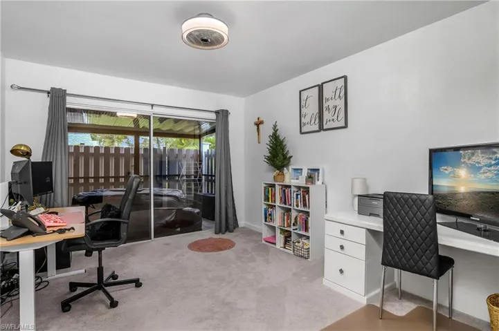 Primary Bedroom Set Up As An Office with Sliders Leading to the Screened-In & Fenced Lanai, and New Light Fixture