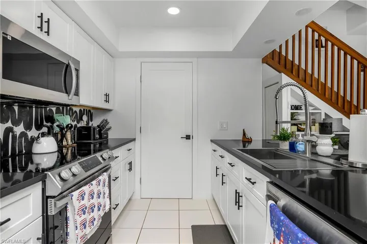 Newly Remodeled Kitchen with Stainless Steel Appliances, Stainless Steel Sink with One Handle Pull Down Faucet, White Shaker Cabinetry with Matte Black Pulls, Black Quartz Counters, Open Shelving & Recessed Lighting