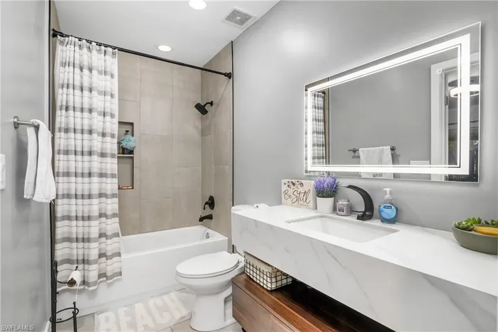 Newly Remodeled Primary Bathroom with Floor To Ceiling Tiled Tub/Shower, Combo, Matte Black Shower and Sink Hardware, Stylish Marble Look Quartz & Wood Vanity with Square Under Counter Sink, & Lighted Vanity Mirror
