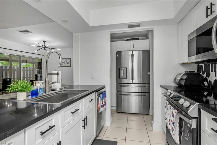 Newly Remodeled Kitchen with Stainless Steel Appliances, Stainless Steel Sink with One Handle Pull Down Faucet, White Shaker Cabinetry with Matte Black Pulls, Black Quartz Counters, Open Shelving & Recessed Lighting