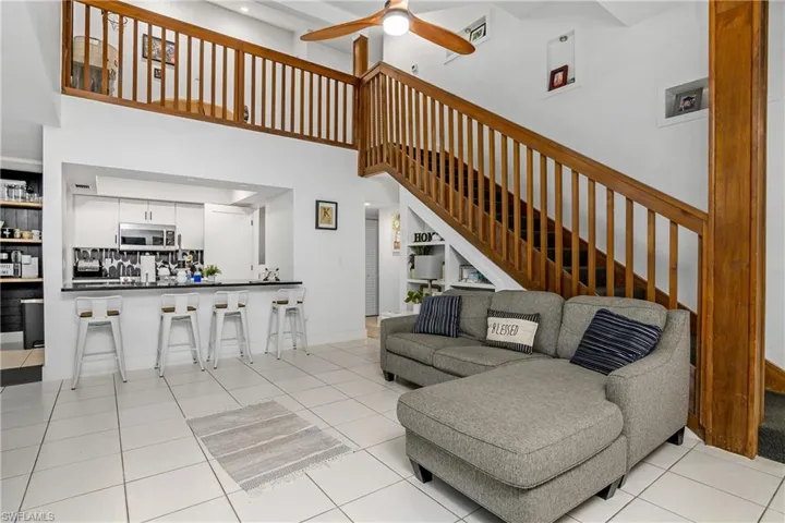 Kitchen, Great Room with Vaulted Ceiling, Built In Under Stairway Shelving, Tile Flooring, New Ceiling Fan, and Carpeted Stairway to the Second Floor Loft