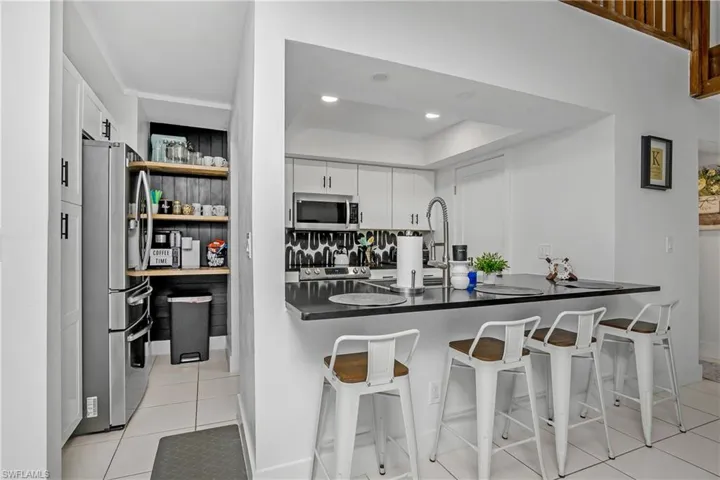 Newly Remodeled Kitchen with Stainless Steel Appliances, Stainless Steel Sink with One Handle Pull Down Faucet, White Shaker Cabinetry with Matte Black Pulls, Black Quartz Counters, Open Shelving & Recessed Lighting