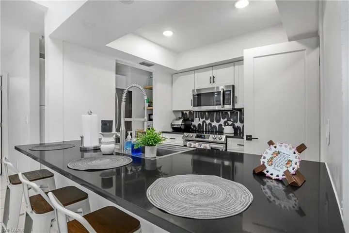 Newly Remodeled Kitchen with Stainless Steel Appliances, Stainless Steel Sink with One Handle Pull Down Faucet, White Shaker Cabinetry with Matte Black Pulls, Black Quartz Counters, Open Shelving & Recessed Lighting