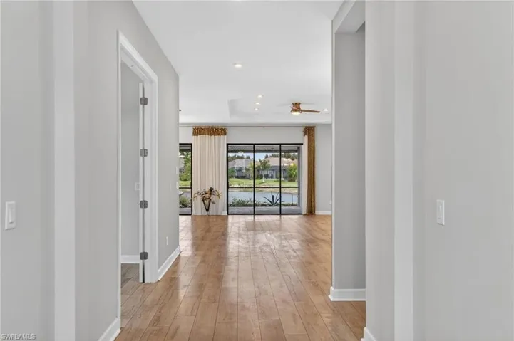 Open-concept living space featuring wood-finish flooring, a tray ceiling with recessed lighting, and a ceiling fan