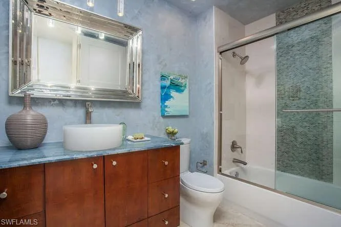 Bathroom with toilet, vanity, and shower / bath combination with glass door