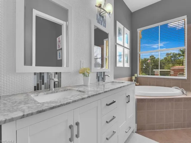 Full bath featuring double vanity, a bath, light tile patterned floors, and tasteful backsplash