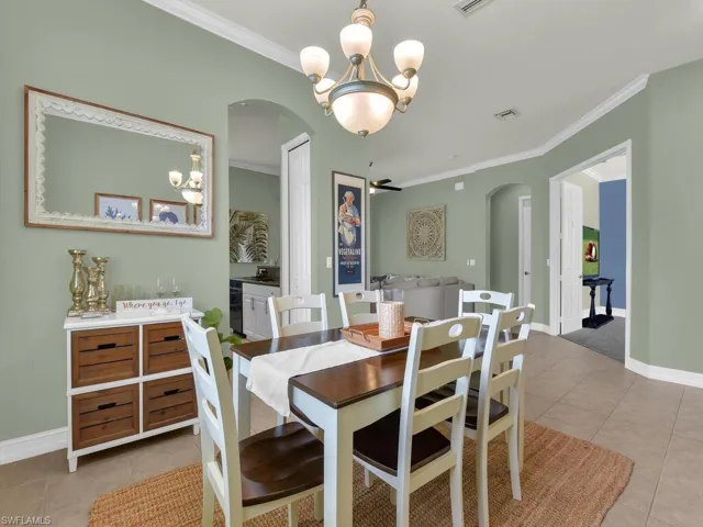 Dining space with light tile patterned floors, a chandelier, arched walkways, and ornamental molding
