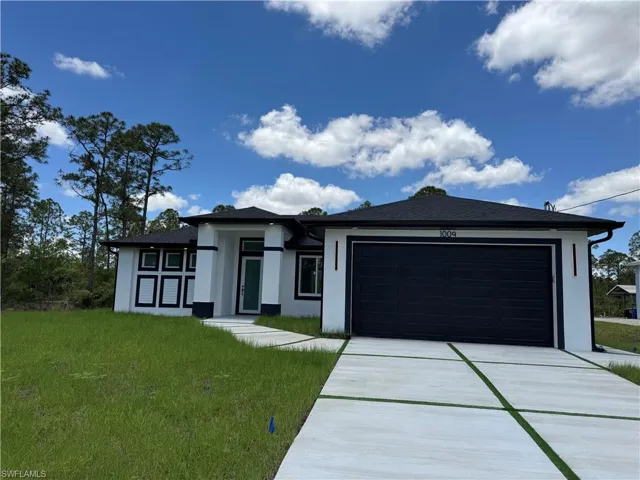 Prairie-style house with stucco siding, an attached garage, driveway, and a front yard