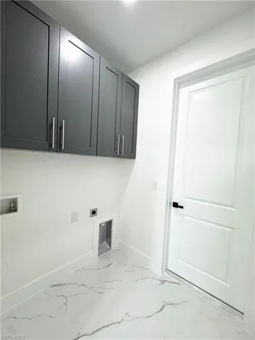 Laundry room featuring electric dryer hookup, cabinet space, hookup for a washing machine, and light marble finish flooring