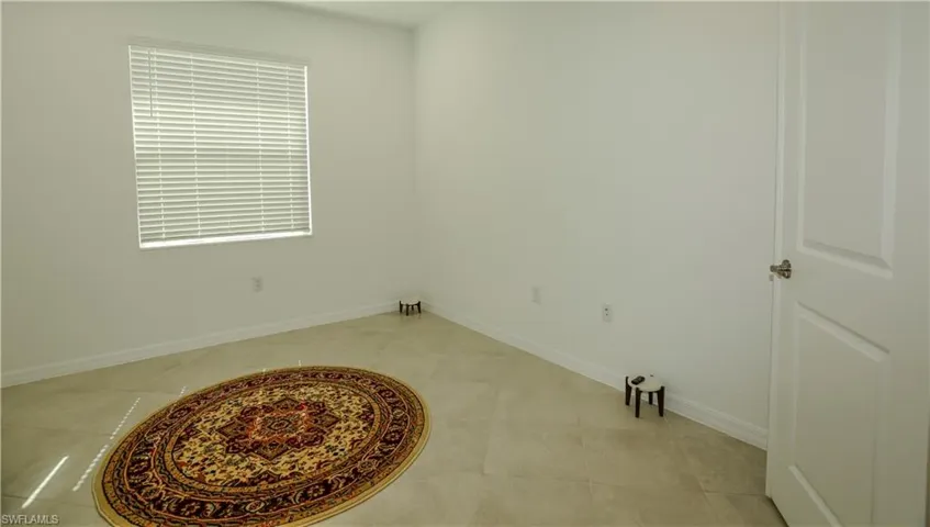 Neutral-toned tile flooring, single-panel interior door with brushed metal hardware, and window equipped with horizontal slat blinds