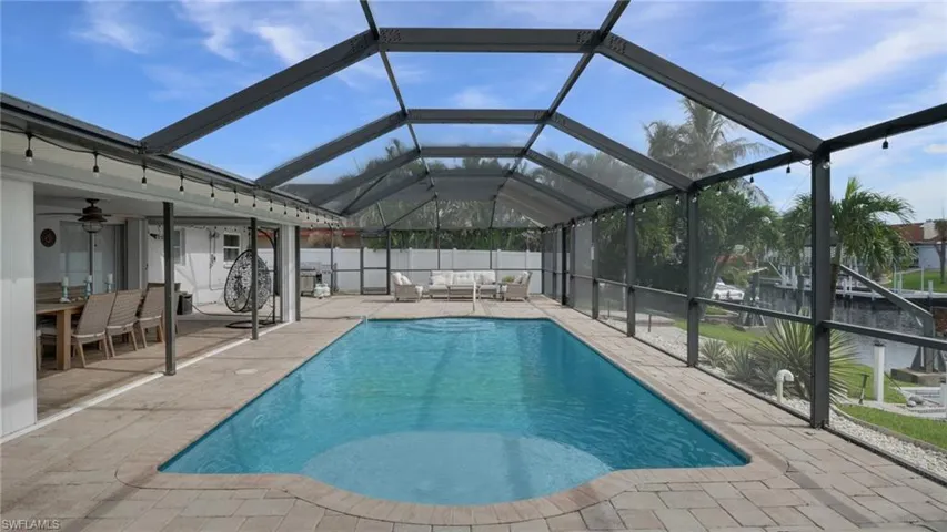 View of pool featuring glass enclosure, a sunroom, outdoor lounge area, and a patio area