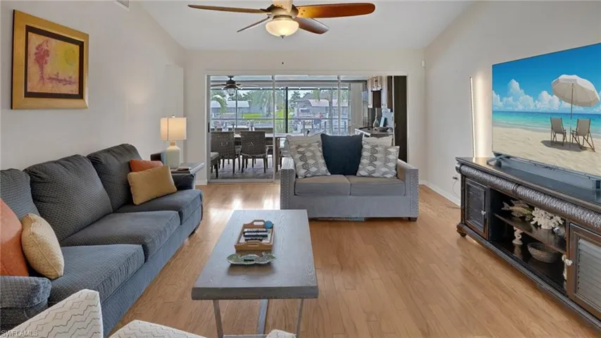 Living room with lofted ceiling, wood finished floors, and a ceiling fan