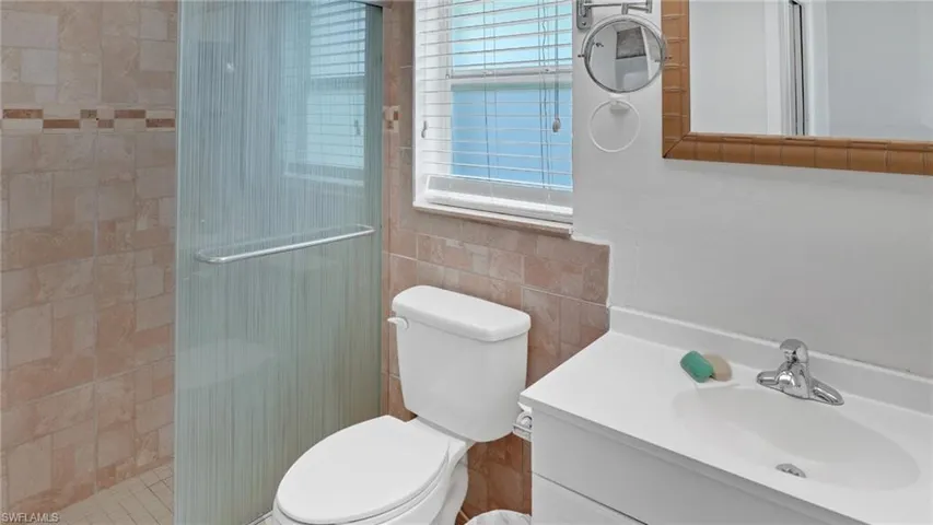 Full bath featuring vanity, a shower stall, and tile walls