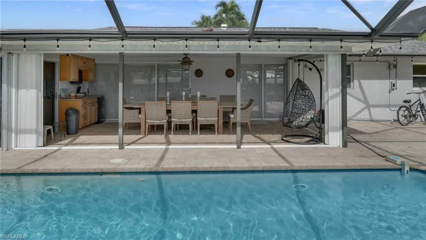 Back of house with a lanai, an outdoor pool, a sunroom, ceiling fan, and outdoor dining area