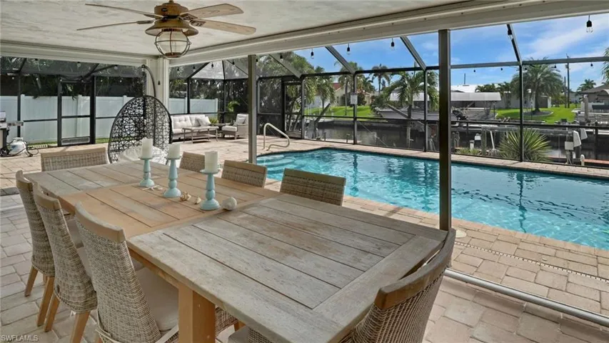 Outdoor pool with a lanai, outdoor dining area, a patio area, and a sunroom
