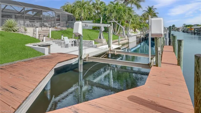 Dock area with a water view, boat lift, and a sunroom
