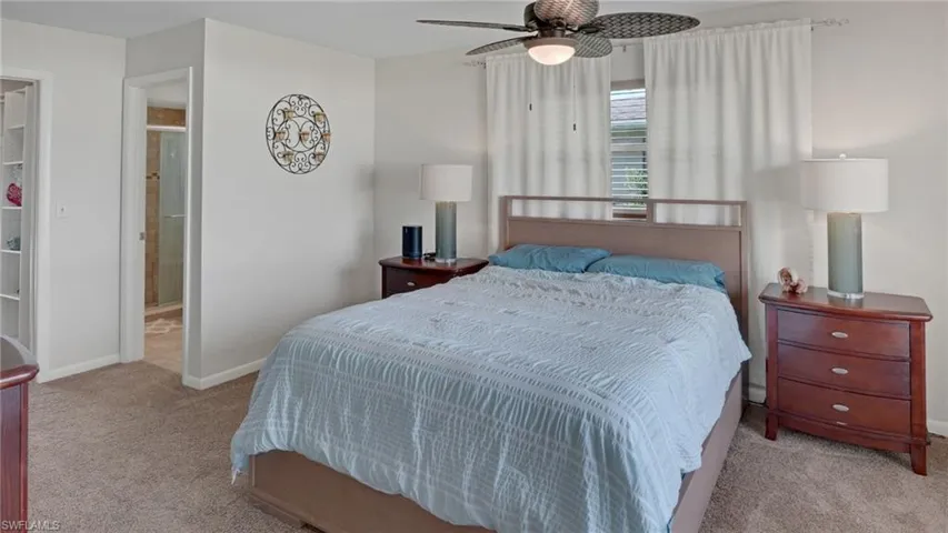 Bedroom featuring light carpet, a ceiling fan, and ensuite bathroom
