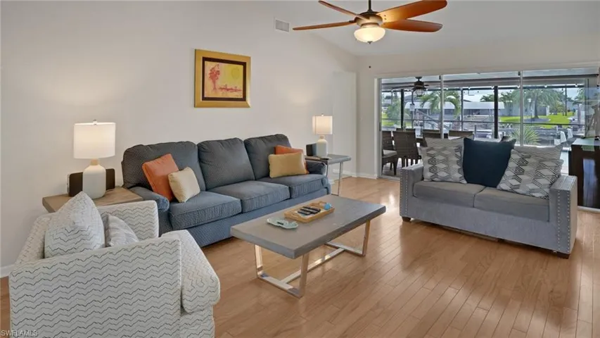 Living area with light wood-style floors, vaulted ceiling, and a ceiling fan
