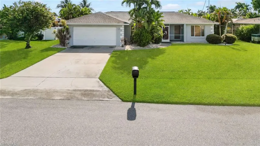 Ranch-style home with driveway, an attached garage, stucco siding, and a front yard