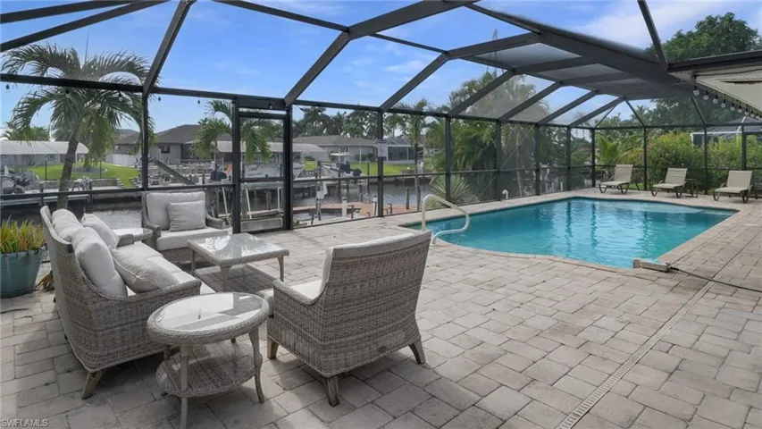 Swimming pool featuring a sunroom, a lanai, a patio area, and a water view