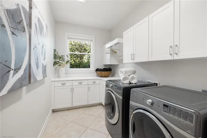 Laundry room featuring light tile patterned flooring, cabinet space, and washing machine and clothes dryer
