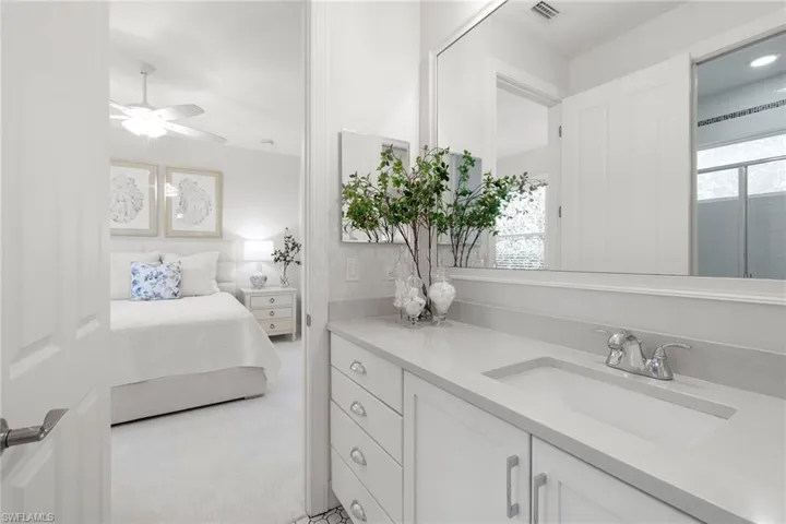 Ensuite bathroom featuring vanity, light carpet, and a ceiling fan