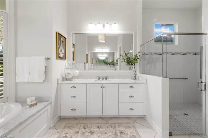 Full bathroom with vanity, a stall shower, and light tile patterned floors