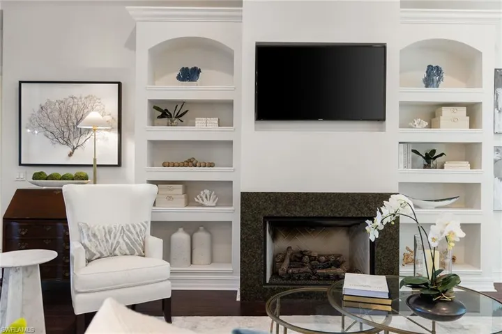 Living room with built in features, wood finished floors, and a fireplace