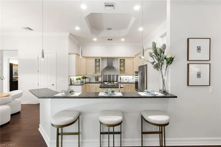 Kitchen featuring a peninsula, a kitchen bar, glass insert cabinets, pendant lighting, and appliances with stainless steel finishes